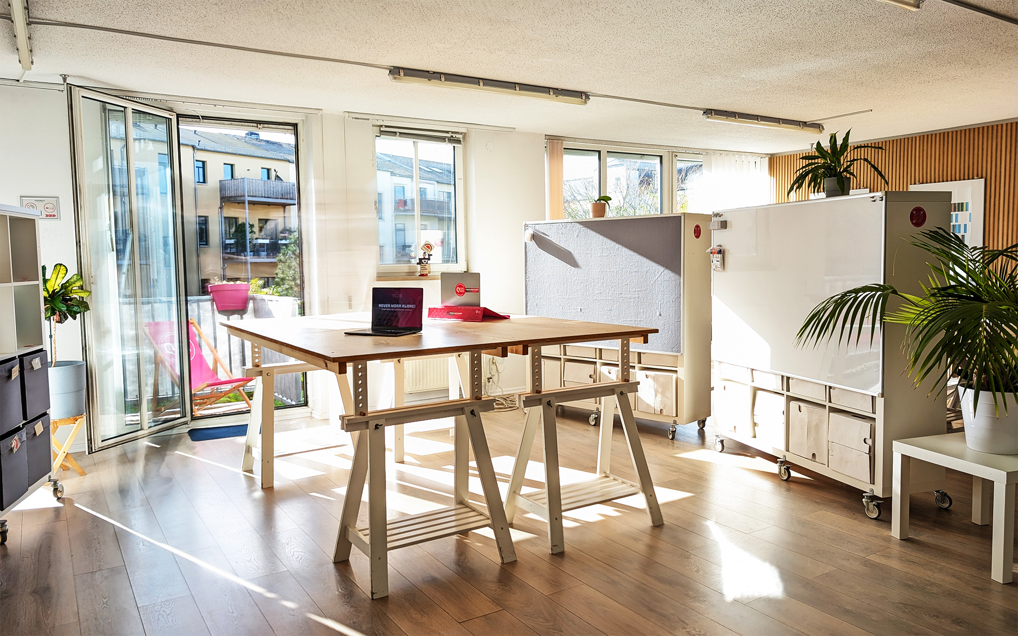 Eventraum mieten Dresden Neustadt: Arbeitsbereich mit Stehtischen, Whiteboard, Pflanzen und Ausgang zum Balkon.