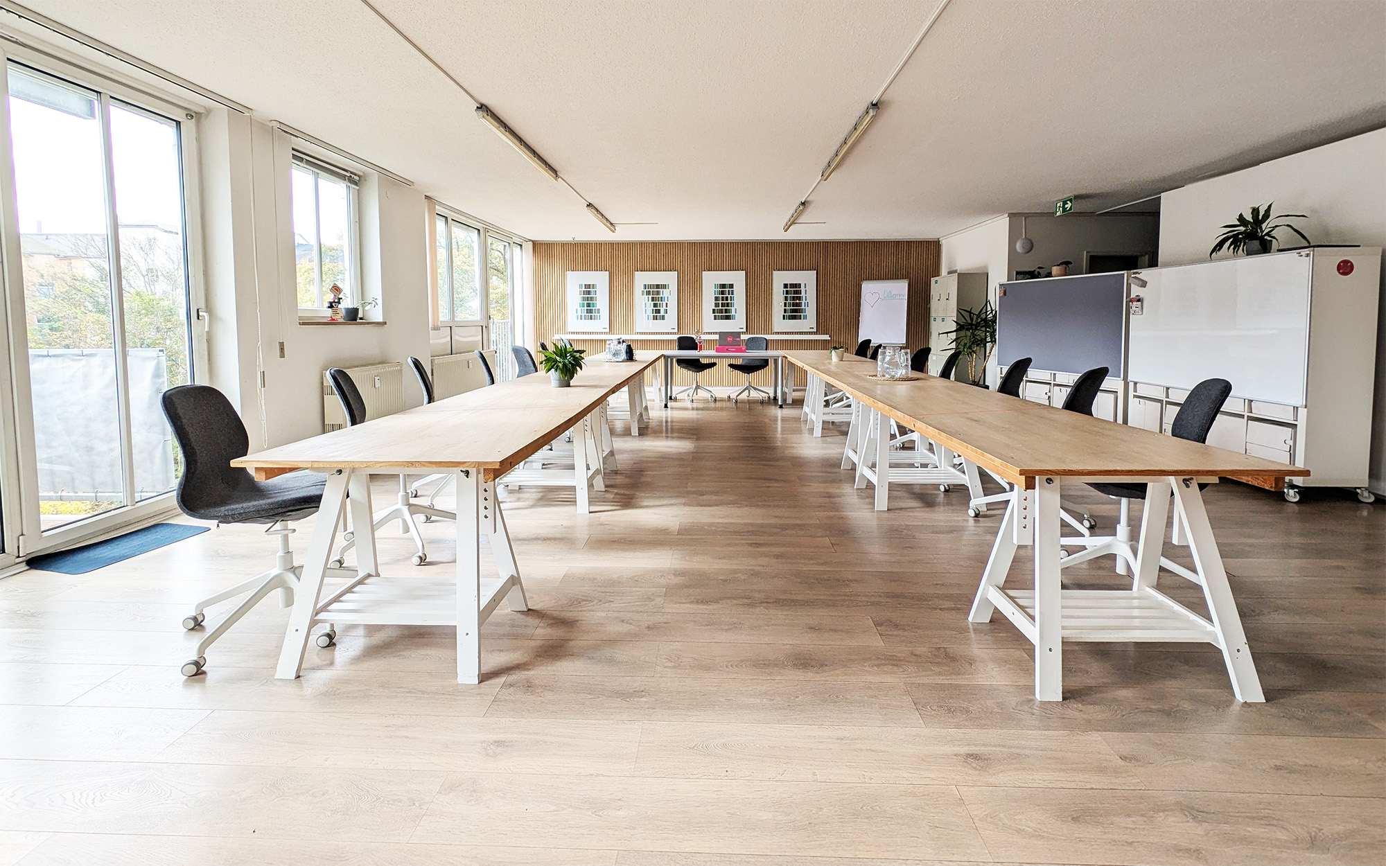 Eventraum mieten Dresden Neustadt: Großer Raum in U-Form mit Holztischen, Fenstern und Whiteboards.